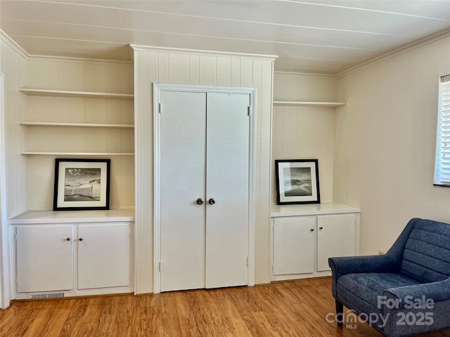 living area featuring light wood finished floors and crown molding