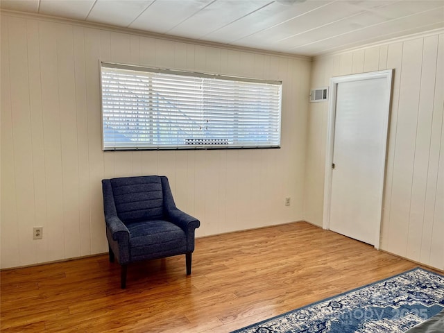 living area with crown molding, wood finished floors, and visible vents