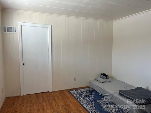 bedroom featuring visible vents, wood finished floors, and ornamental molding