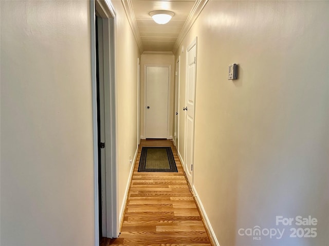 hallway with crown molding, baseboards, and light wood finished floors