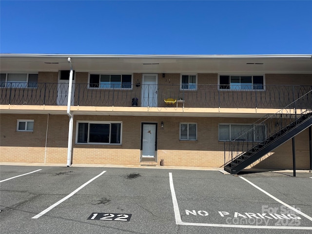 view of property with stairway and uncovered parking