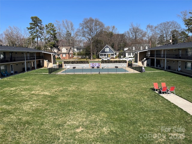 view of yard with a residential view, a community pool, and fence