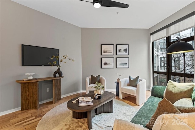 living area with ceiling fan, baseboards, and wood finished floors