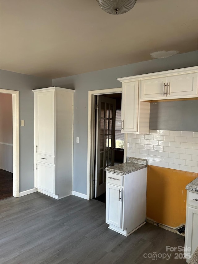 kitchen featuring dark wood finished floors, light stone counters, tasteful backsplash, and white cabinetry