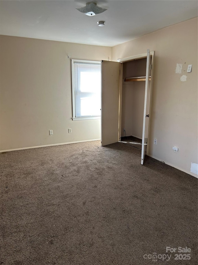 unfurnished bedroom featuring a closet and dark carpet