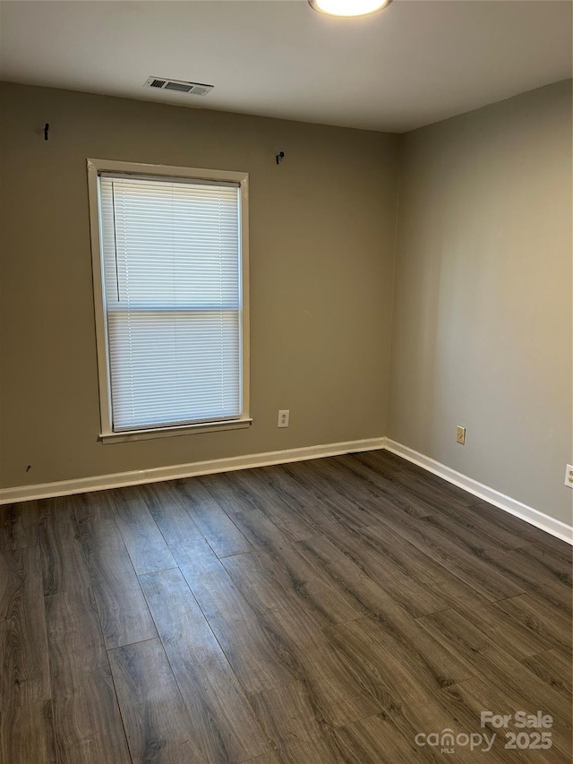 spare room with dark wood finished floors, baseboards, and visible vents