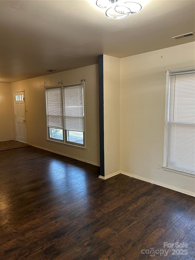 unfurnished room featuring dark wood finished floors, baseboards, and visible vents