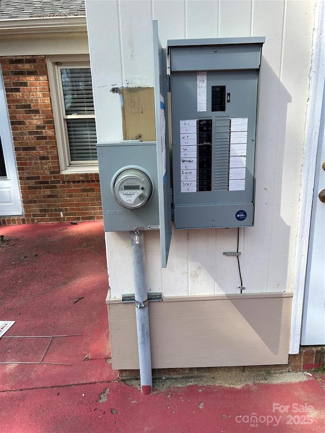 details featuring electric panel, brick siding, and electric meter