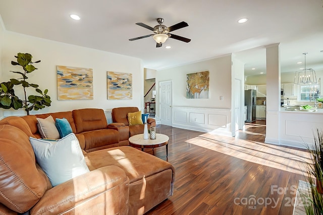 living area featuring stairway, ornamental molding, recessed lighting, ceiling fan with notable chandelier, and wood finished floors