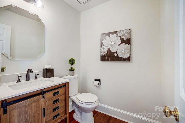 bathroom featuring toilet, vanity, baseboards, and wood finished floors