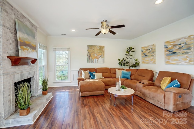 living area featuring wood finished floors, recessed lighting, ceiling fan, ornamental molding, and a brick fireplace