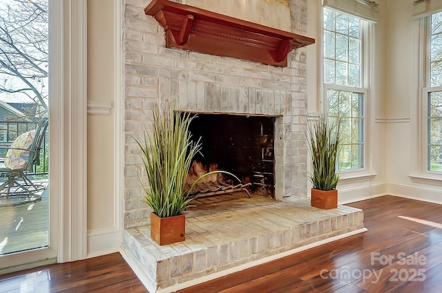 details featuring baseboards, a fireplace with raised hearth, and wood finished floors