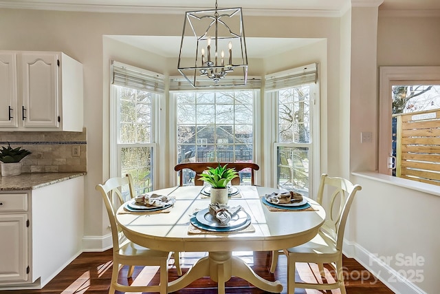 dining space with an inviting chandelier, crown molding, baseboards, and dark wood-type flooring