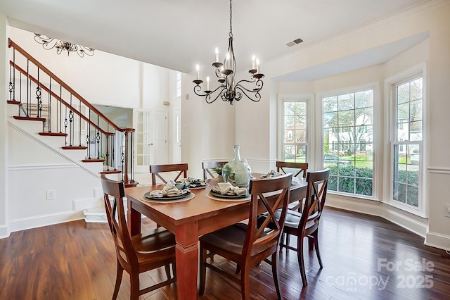 dining space with visible vents, a notable chandelier, dark wood finished floors, baseboards, and stairs