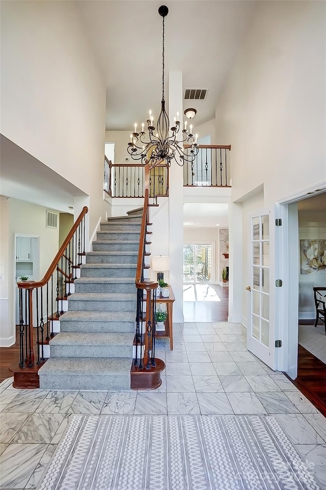 stairs with visible vents, marble finish floor, baseboards, and a towering ceiling