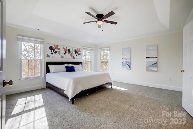 carpeted bedroom featuring visible vents, ceiling fan, baseboards, and a tray ceiling