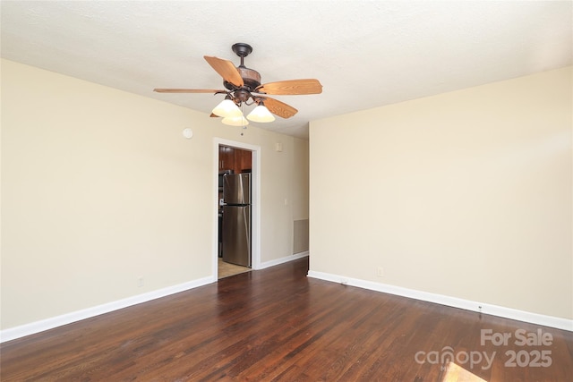 spare room with dark wood-type flooring, a ceiling fan, and baseboards