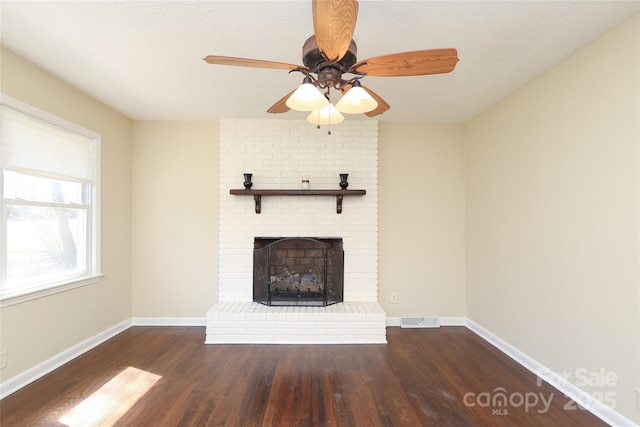 unfurnished living room featuring visible vents, baseboards, wood finished floors, and a fireplace