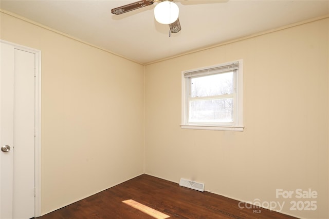 unfurnished room with ceiling fan, visible vents, and dark wood-style floors