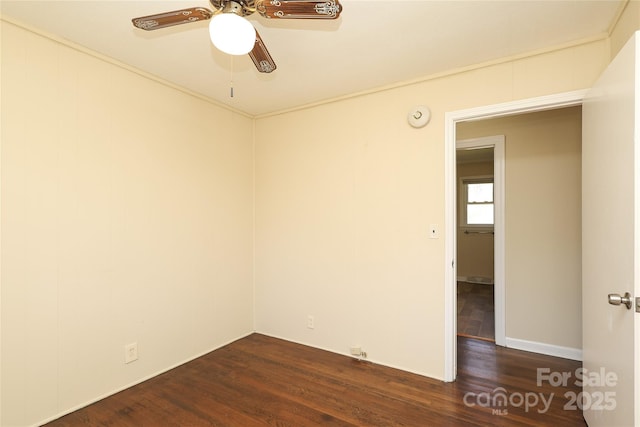 empty room with a ceiling fan, ornamental molding, and dark wood-style flooring