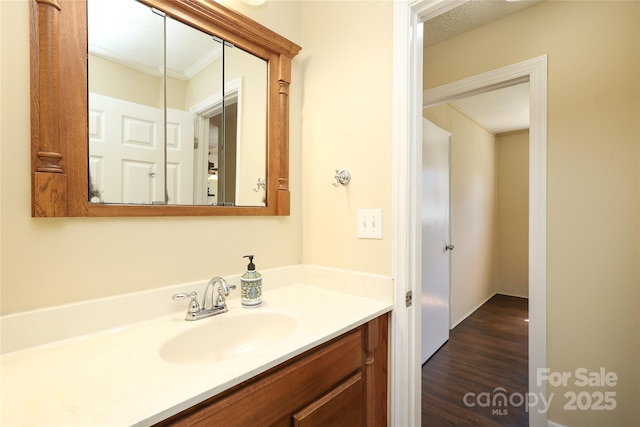 bathroom with wood finished floors, ornamental molding, and vanity