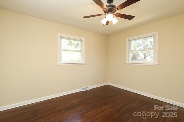 empty room featuring visible vents, baseboards, dark wood finished floors, and a ceiling fan