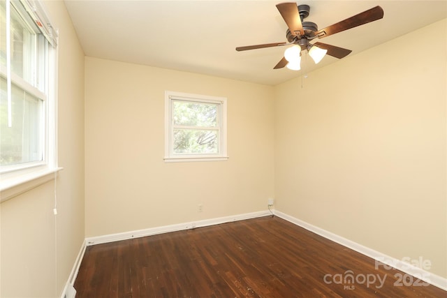 empty room featuring dark wood finished floors, baseboards, and ceiling fan