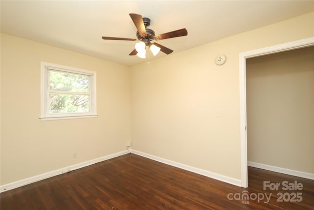 empty room featuring dark wood finished floors, baseboards, and ceiling fan