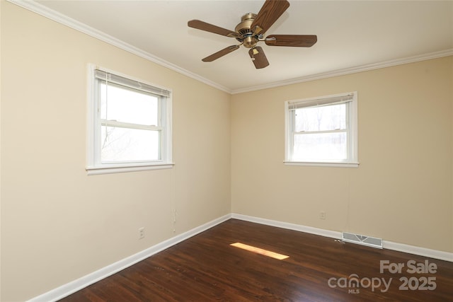 spare room with visible vents, a healthy amount of sunlight, ornamental molding, and dark wood-style floors