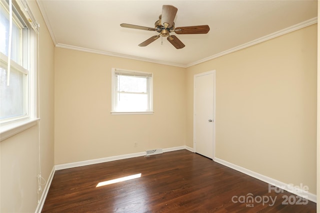 unfurnished room with crown molding, visible vents, dark wood-type flooring, and baseboards