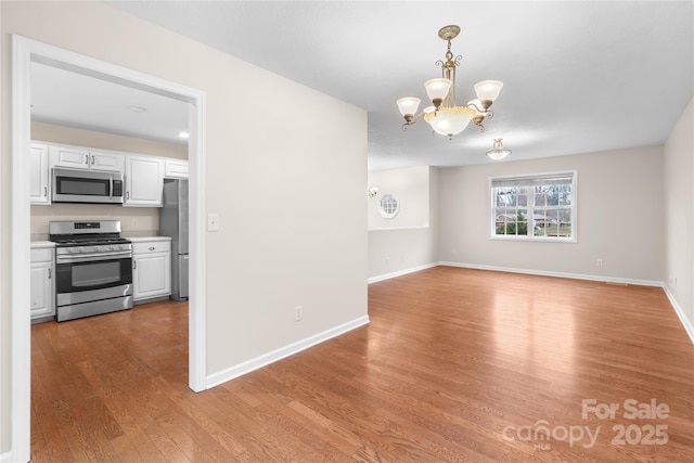 interior space featuring light wood-style flooring, baseboards, and an inviting chandelier