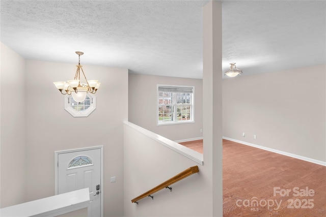 entryway featuring baseboards, a textured ceiling, and a chandelier