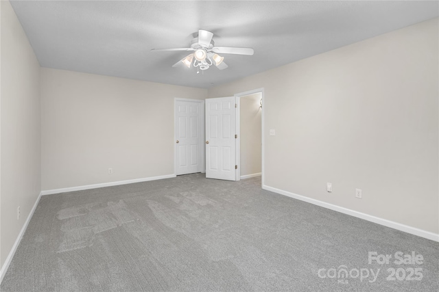 spare room with carpet flooring, a ceiling fan, and baseboards