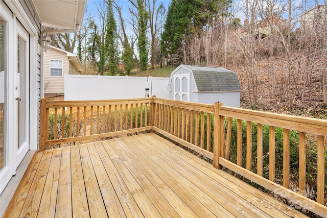 wooden terrace featuring a storage unit, an outdoor structure, and fence