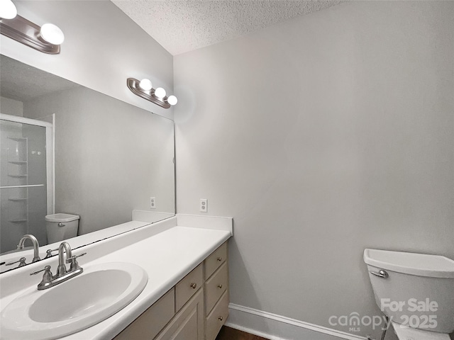 full bathroom with a shower stall, a textured ceiling, toilet, and vanity