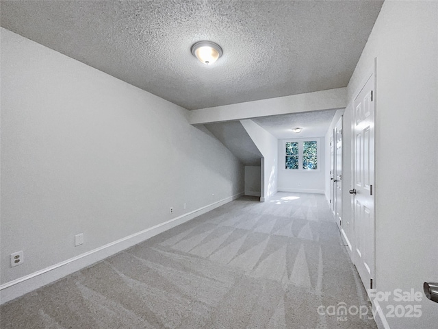 additional living space with carpet flooring, baseboards, and a textured ceiling