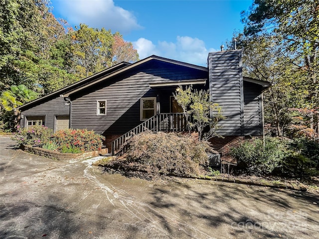 view of front of home with a garage, a chimney, and driveway