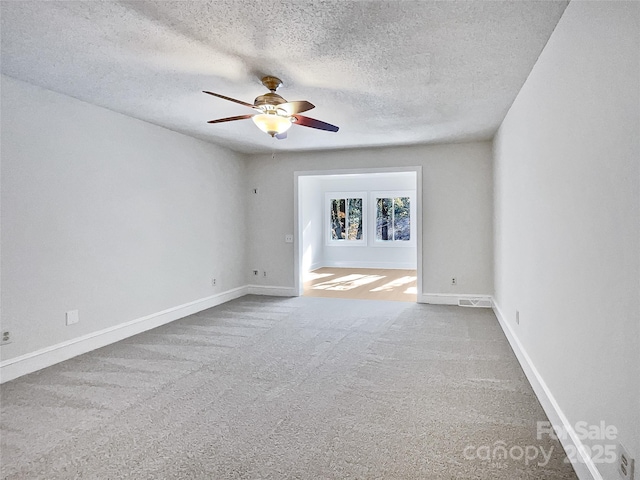 carpeted empty room with baseboards, a textured ceiling, and a ceiling fan