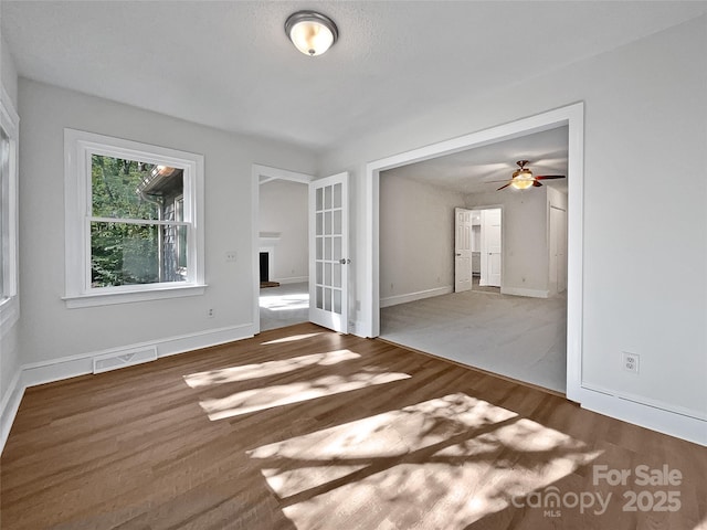 empty room featuring visible vents, baseboards, wood finished floors, and french doors