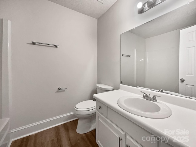 full bath with baseboards, toilet, vanity, wood finished floors, and a textured ceiling