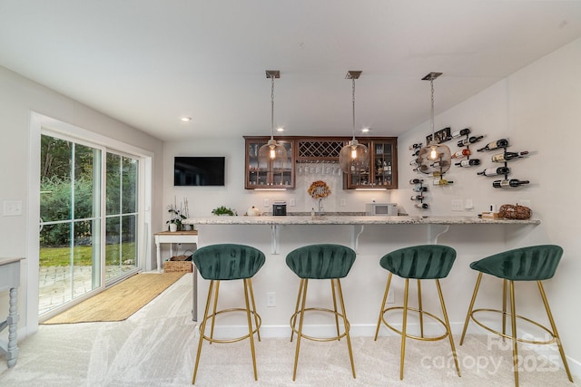 kitchen with glass insert cabinets, a kitchen breakfast bar, light colored carpet, and a peninsula