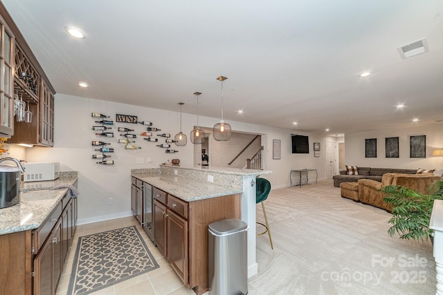 kitchen featuring visible vents, a peninsula, recessed lighting, glass insert cabinets, and a kitchen bar