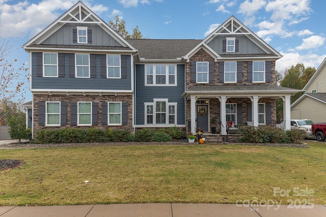 view of front of house featuring stone siding, covered porch, board and batten siding, and a front yard