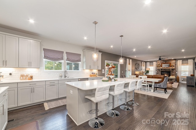 kitchen with backsplash, dark wood finished floors, a kitchen bar, light countertops, and a sink