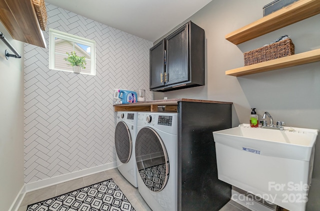 washroom featuring an accent wall, light tile patterned floors, separate washer and dryer, cabinet space, and a sink