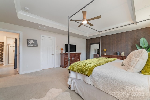 bedroom featuring light carpet, baseboards, a tray ceiling, and a ceiling fan