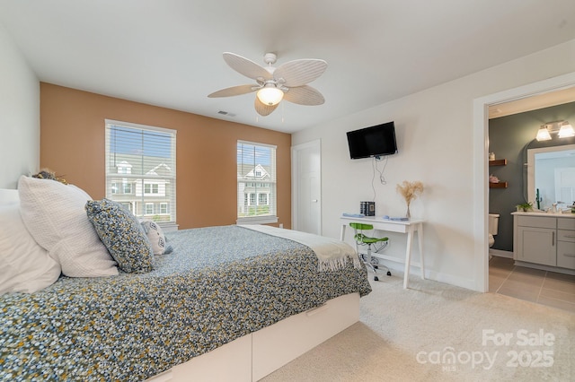 bedroom featuring a ceiling fan, visible vents, baseboards, light colored carpet, and connected bathroom