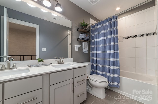 bathroom featuring tile patterned flooring, toilet, visible vents, and a sink