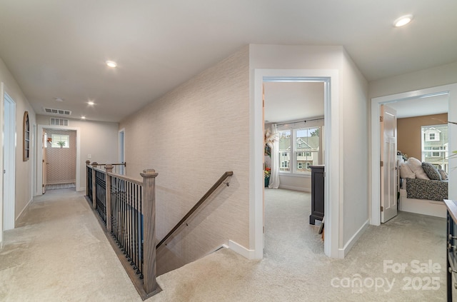 hallway featuring an upstairs landing, visible vents, recessed lighting, and light carpet