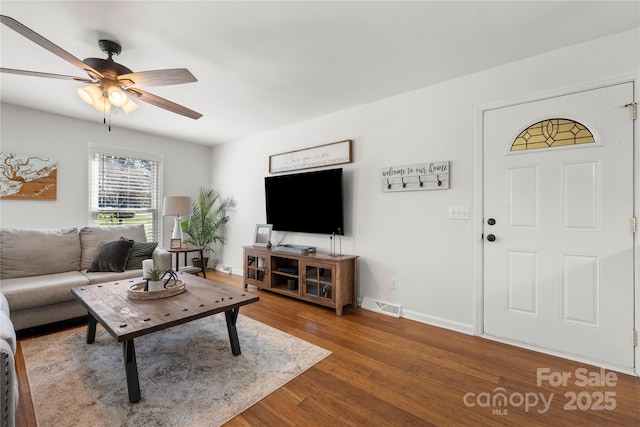 living room with visible vents, baseboards, ceiling fan, and wood finished floors